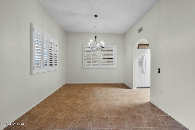 unfurnished dining area with a wealth of natural light, a textured ceiling, and a notable chandelier