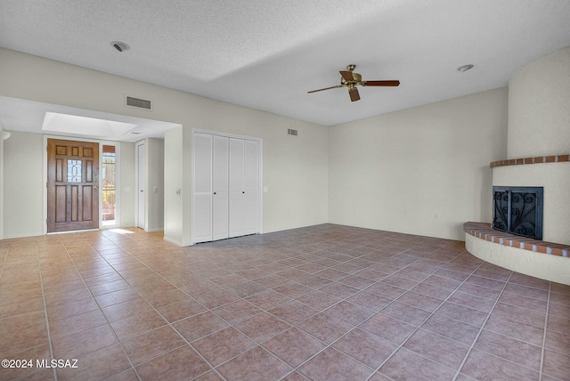 unfurnished living room with tile patterned floors, ceiling fan, and a textured ceiling