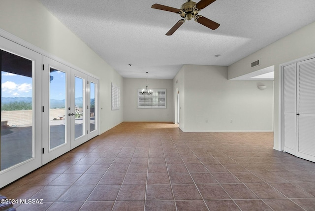 spare room with tile patterned floors, french doors, a textured ceiling, and ceiling fan with notable chandelier