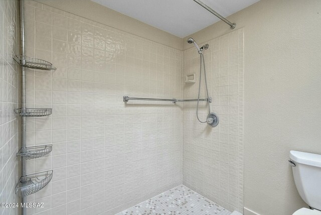 bathroom with tiled shower and toilet