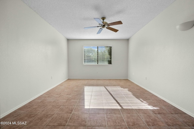 tiled empty room with ceiling fan and a textured ceiling