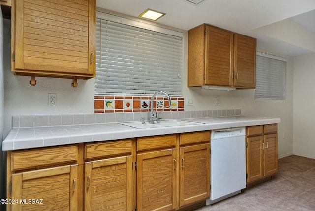 kitchen featuring light tile patterned flooring, dishwasher, tile countertops, and sink