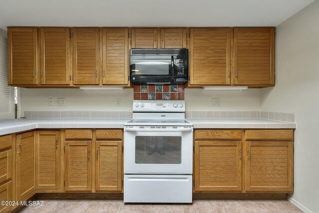 kitchen featuring white appliances, sink, a skylight, ceiling fan, and a tray ceiling