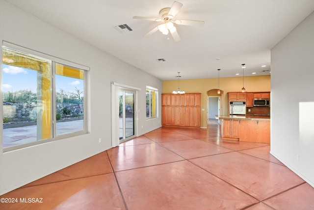 unfurnished living room with ceiling fan with notable chandelier and light tile patterned floors