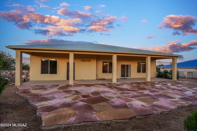 back house at dusk with a patio area