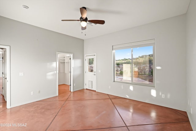 unfurnished bedroom featuring a spacious closet, a closet, ceiling fan, and light tile patterned flooring