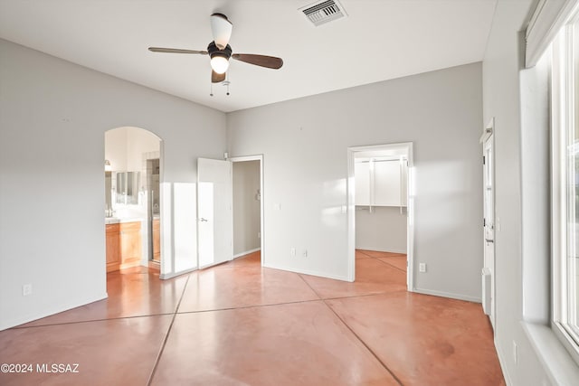 unfurnished bedroom featuring ceiling fan, a closet, a walk in closet, and ensuite bath