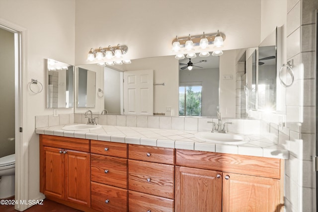 bathroom with backsplash, ceiling fan, vanity, and toilet