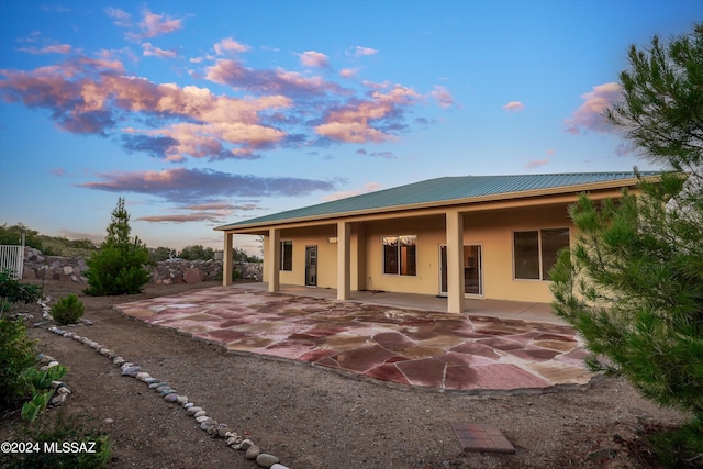 back house at dusk featuring a patio area