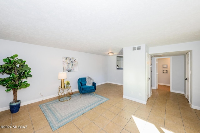 living area featuring light tile patterned flooring, visible vents, and baseboards