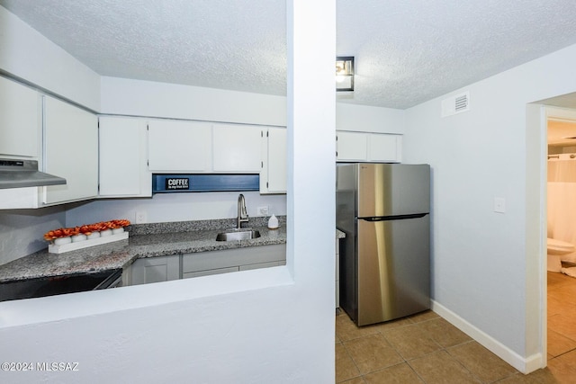 kitchen featuring white cabinetry, sink, stainless steel fridge, light tile patterned floors, and exhaust hood