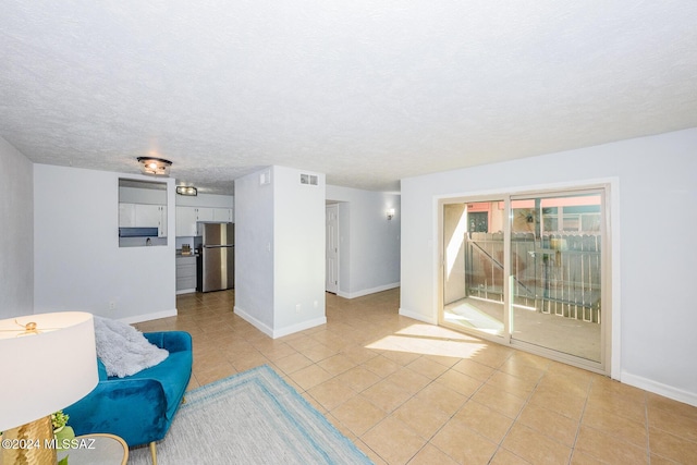 sitting room featuring light tile patterned floors, baseboards, visible vents, and a textured ceiling