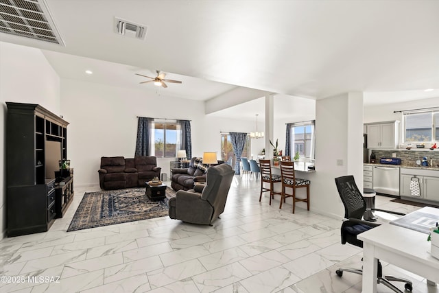 living room with ceiling fan with notable chandelier