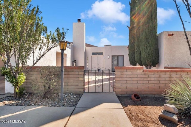 exterior space with a gate, a chimney, a fenced front yard, and stucco siding