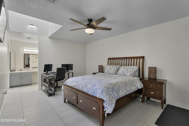 bedroom with light tile patterned floors, a textured ceiling, and ensuite bath