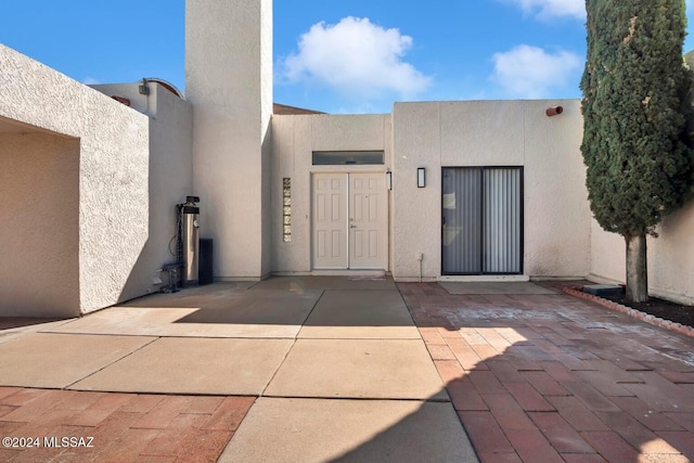 view of exterior entry with a patio area and stucco siding