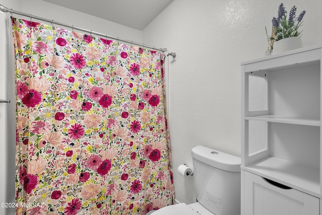 bathroom featuring curtained shower, toilet, and a textured wall