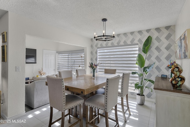 tiled dining space with a chandelier, a healthy amount of sunlight, a textured ceiling, and baseboards