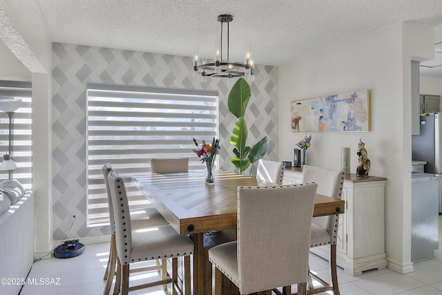 dining space featuring light tile patterned floors, a textured ceiling, an accent wall, and an inviting chandelier