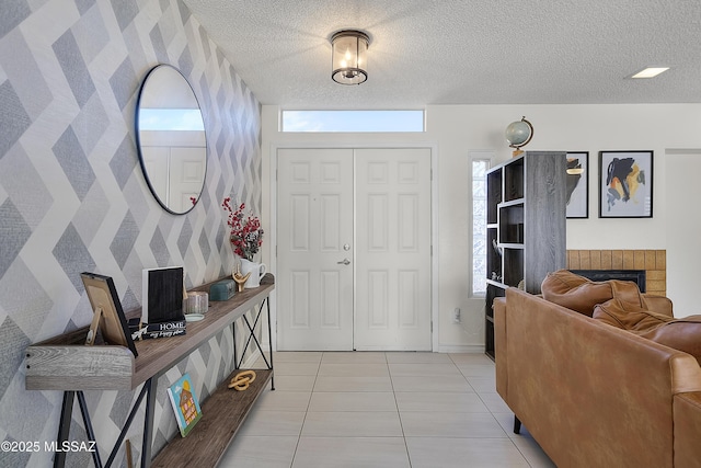 foyer featuring a textured ceiling, a brick fireplace, and light tile patterned flooring