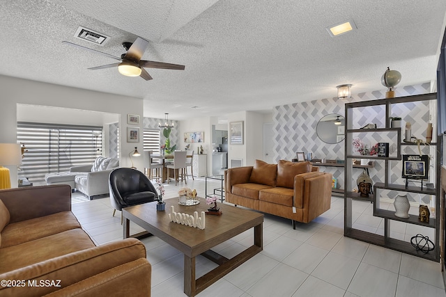 living area featuring light tile patterned floors, visible vents, a textured ceiling, and a ceiling fan