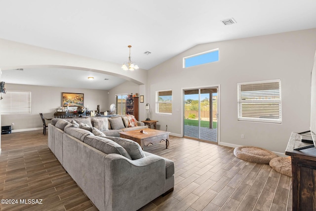 living room featuring dark hardwood / wood-style flooring, lofted ceiling, and an inviting chandelier