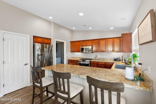 kitchen with kitchen peninsula, a breakfast bar, stainless steel appliances, and sink