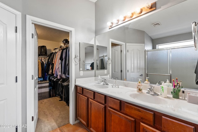 bathroom featuring tile patterned floors, vanity, and a shower with shower door