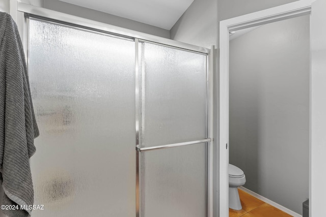 bathroom with tile patterned flooring, toilet, and a shower with shower door