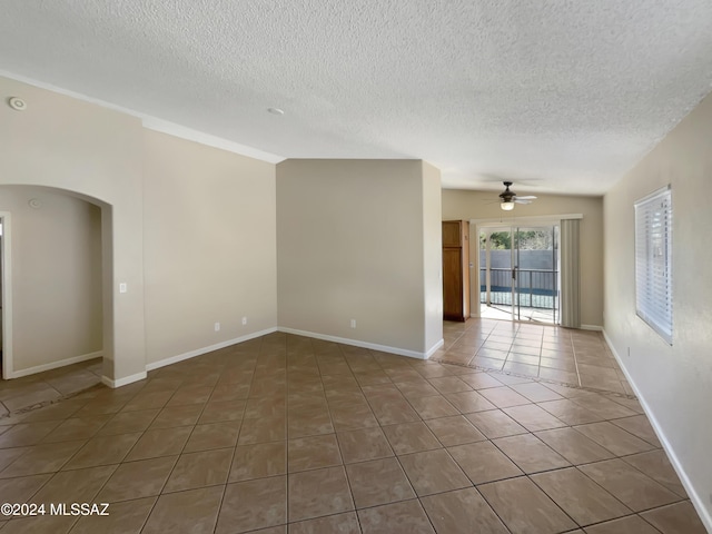 empty room featuring a textured ceiling, dark tile patterned floors, and ceiling fan