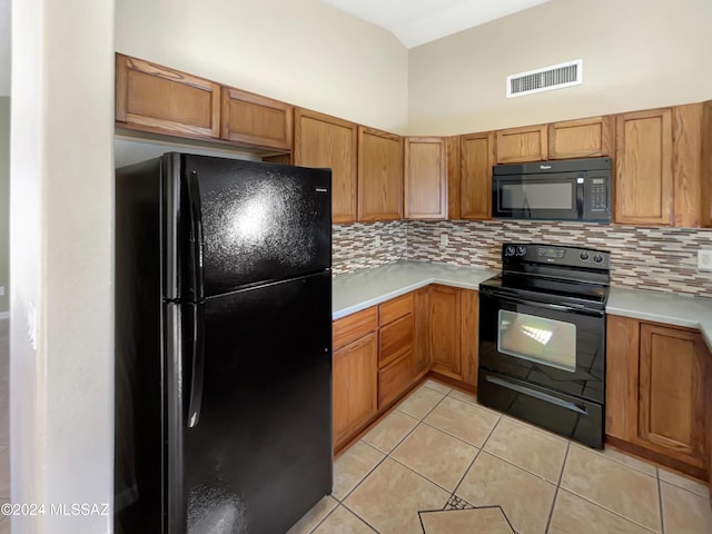 kitchen featuring tasteful backsplash, light tile patterned floors, and black appliances