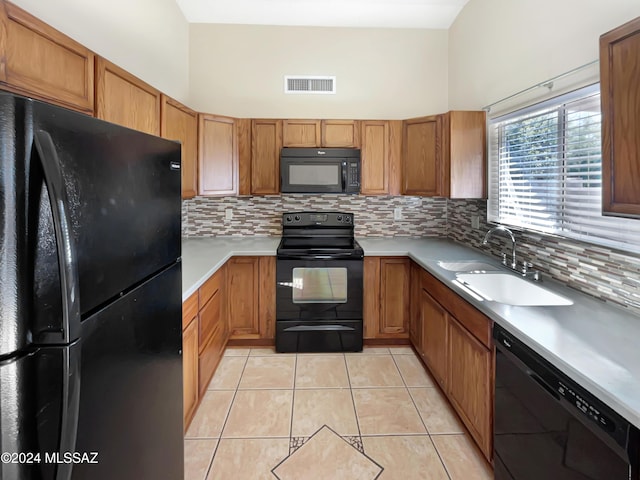 kitchen featuring backsplash, sink, light tile patterned floors, and black appliances