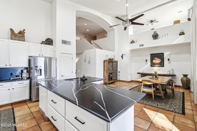 kitchen featuring white cabinetry, ceiling fan, sink, stainless steel fridge with ice dispenser, and a kitchen island with sink