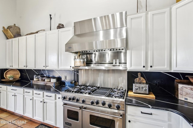 kitchen with tasteful backsplash, white cabinetry, double oven range, and wall chimney range hood