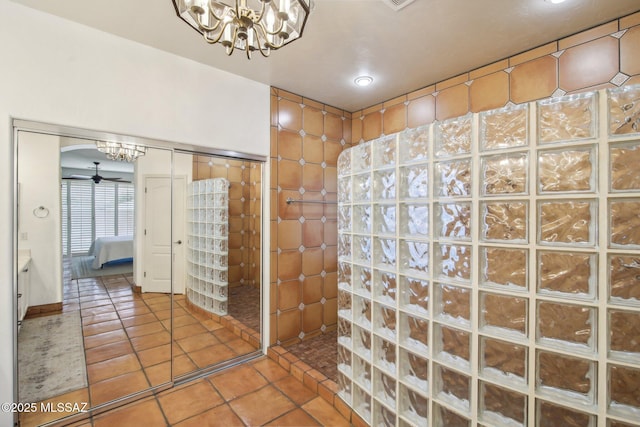 bathroom featuring tile patterned flooring, ceiling fan with notable chandelier, and walk in shower