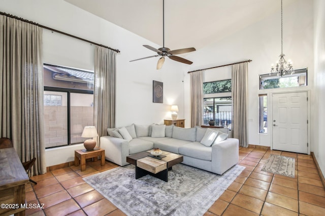 tiled living room with ceiling fan with notable chandelier and high vaulted ceiling