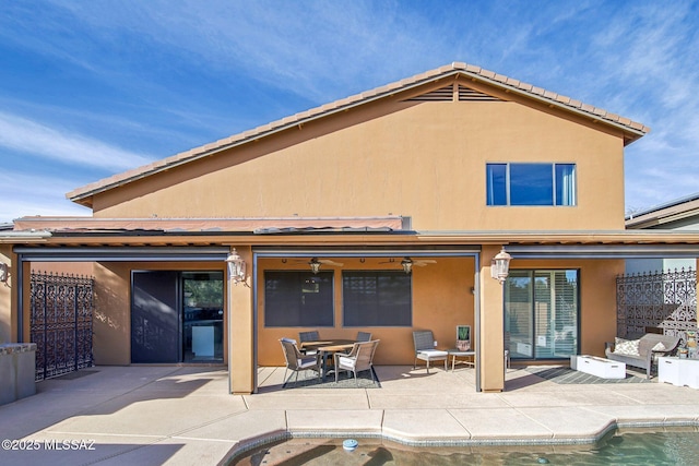 rear view of property with ceiling fan and a patio area