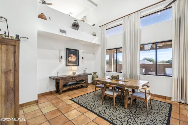 tiled dining space featuring ceiling fan and a high ceiling