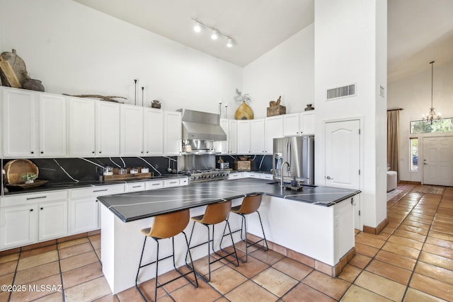 kitchen with high vaulted ceiling, ventilation hood, white cabinets, a center island with sink, and stainless steel refrigerator with ice dispenser