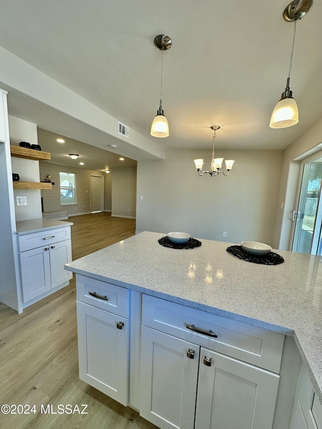 kitchen with decorative light fixtures, light stone counters, white cabinetry, and light wood-type flooring