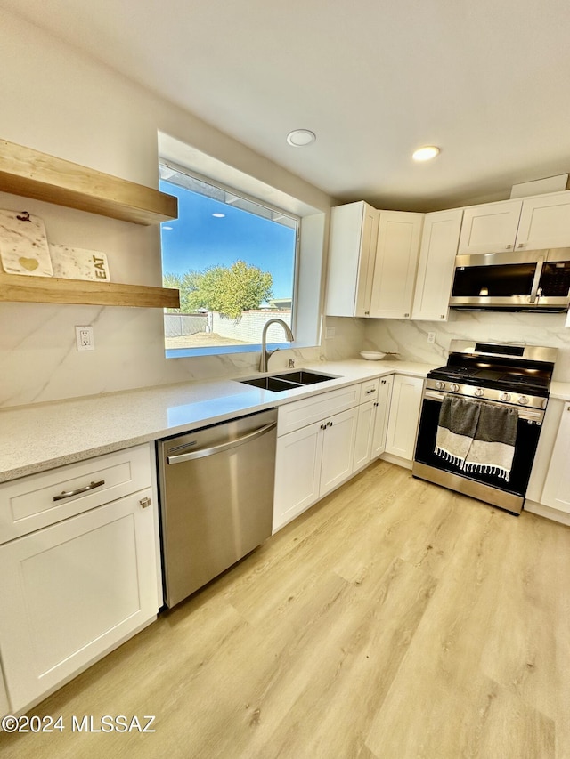 kitchen with white cabinetry, sink, light hardwood / wood-style floors, and appliances with stainless steel finishes