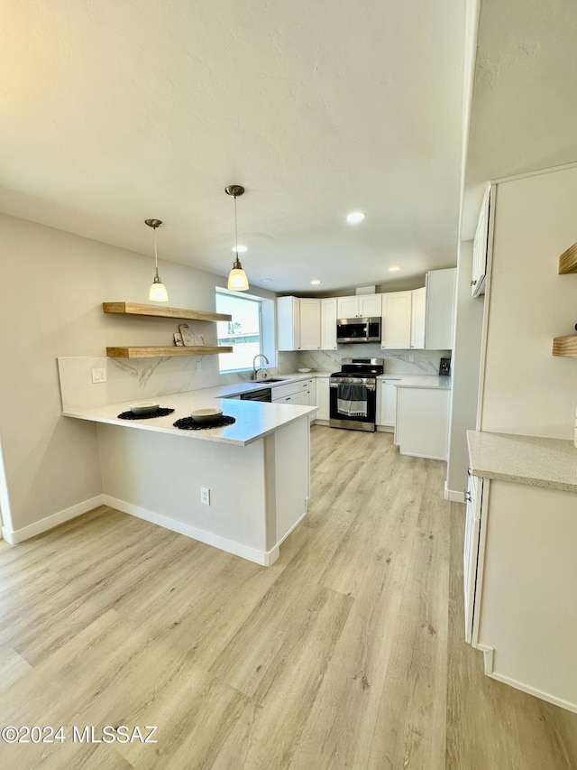 kitchen featuring kitchen peninsula, appliances with stainless steel finishes, white cabinets, light hardwood / wood-style floors, and hanging light fixtures