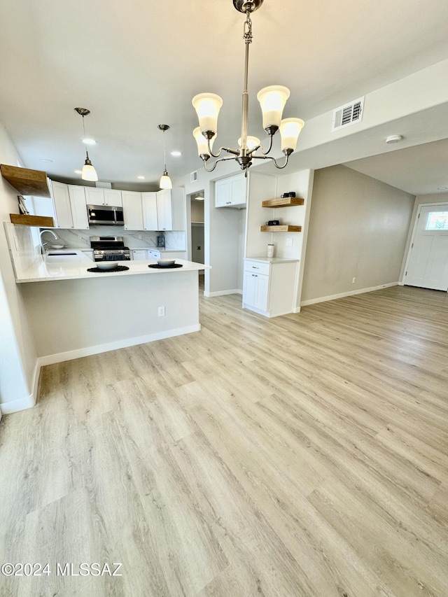 kitchen with hanging light fixtures, kitchen peninsula, appliances with stainless steel finishes, white cabinets, and light wood-type flooring