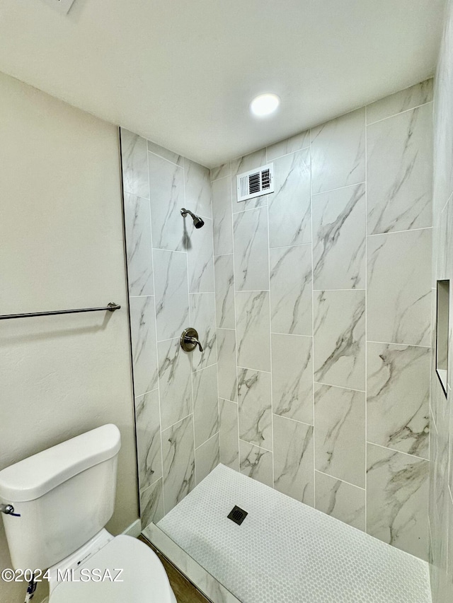 bathroom featuring tiled shower and toilet