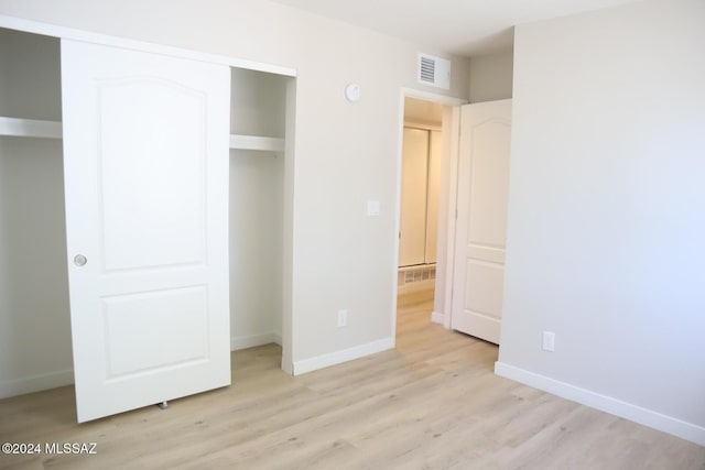 unfurnished bedroom with light wood-type flooring and a closet