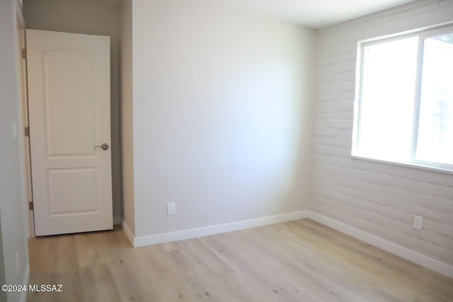 spare room with light hardwood / wood-style flooring and brick wall