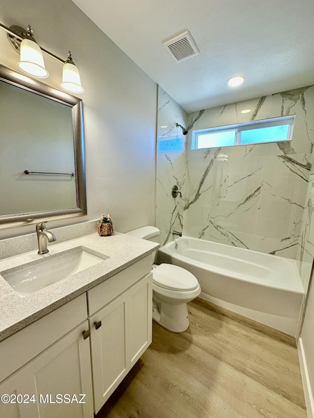 full bathroom featuring hardwood / wood-style floors, tiled shower / bath combo, toilet, and vanity