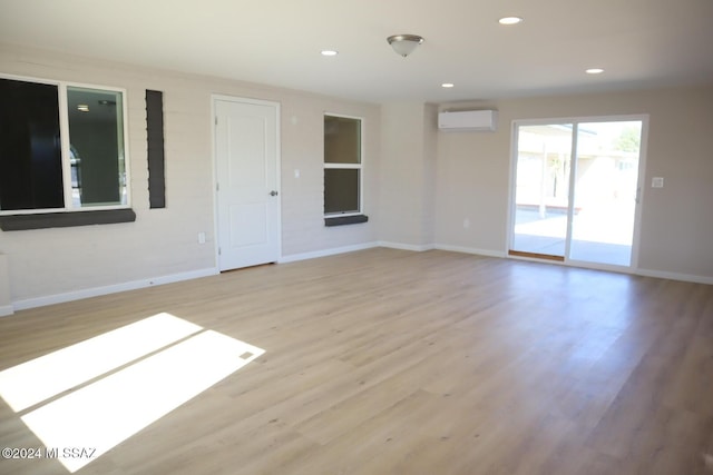 unfurnished room featuring a wall unit AC and light wood-type flooring