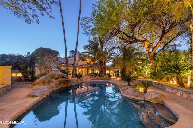 pool at dusk featuring a patio area