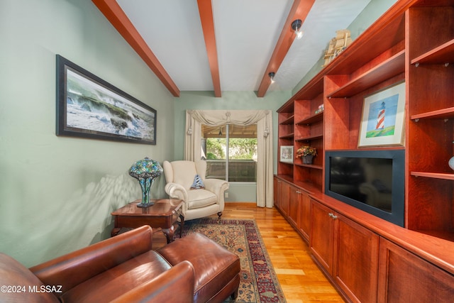 living room featuring beamed ceiling and light hardwood / wood-style floors